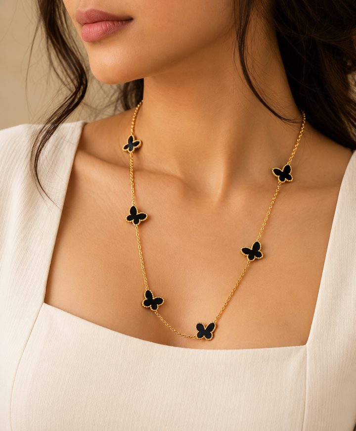 Model wearing a long gold chain with black butterfly charms