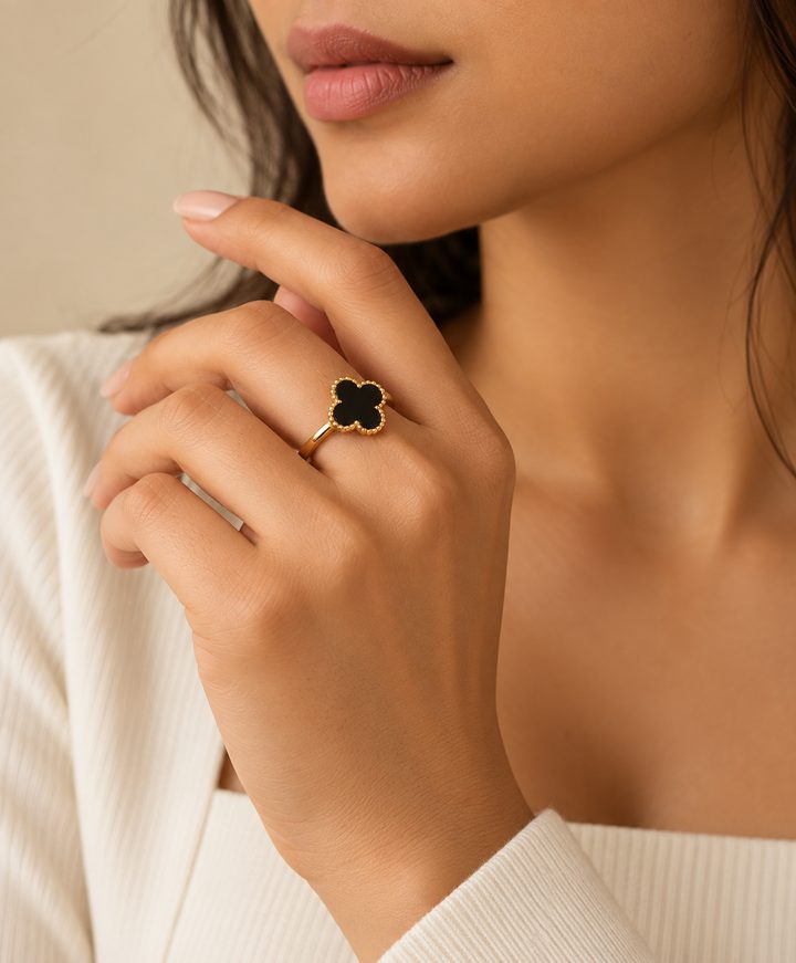 Model wearing a gold ring with a black four-petal motif