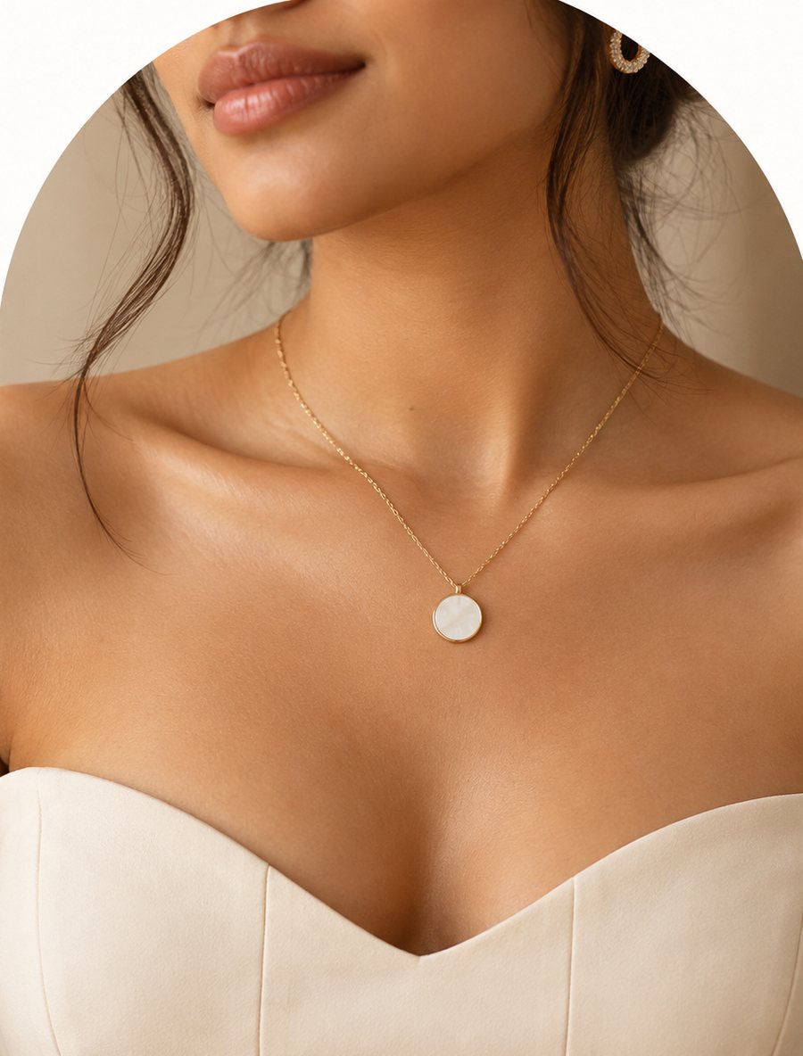 Model wearing a gold chain necklace with a round mother-of-pearl pendant